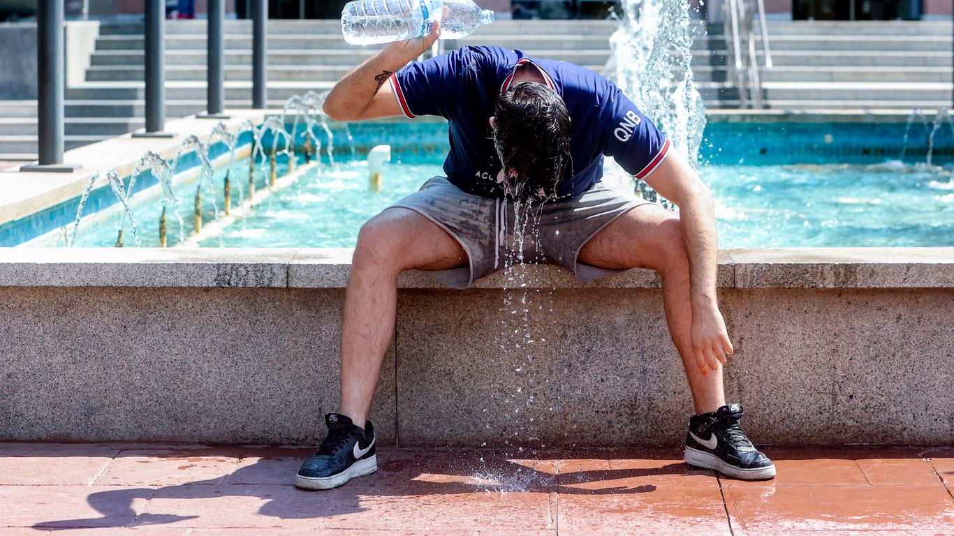 A young man throws a bottle of water over himself