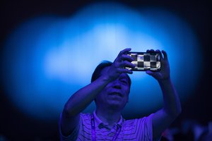 file - A spectator takes a cellphone photo of the CHAIN Cup at the China National Convention Center in Beijing, Saturday, June 30, 2018. A computer running artificial intelligence software defeated two teams of human doctors in accurately recognizing maladies in magnetic resonance images on Saturday, in a contest that was billed as the world's first competition in neuroimaging between AI and human experts. (AP Photo/Mark Schiefelbein)