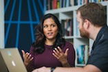 Woman animatedly talking to a coworker in front of bookshelves