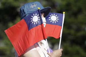 In this Sunday, Oct. 10, 2021, file photo, a woman holds up Taiwan national flags during National Day celebrations in front of the Presidential Building in Taipei, Taiwan