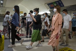 Commuters walk through a subway station during the morning rush hour in the central business district in Beijing, Tuesday, Aug. 9, 2022