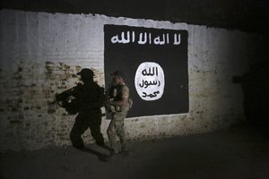 In this March 1, 2017 file photo, an Iraqi soldier inspects a recently-discovered train tunnel, adorned with an Islamic State group flag, that belonged to the former Baghdad to Mosul line, that was turned it to a training camp for IS fighters, in western Mosul, Iraq.