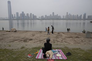 File - A child wearing a mask against the coronavirus rests along the Yangtze River in Wuhan in central China's Hubei province on April 5, 2020.