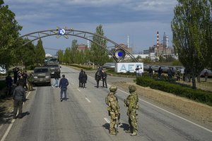 Russian servicemen stand on the road towards the Zaporizhzhia Nuclear Power Station in territory under Russian military control, southeastern Ukraine, Sunday, May 1, 2022