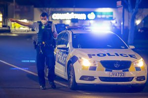 A police officer gestures as he stand outside the site of a knife attack at a supermarket in Auckland, New Zealand, Friday, Sept. 3, 2021