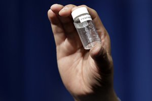 FILE - A reporter holds up an example of the amount of fentanyl that can be deadly after a news conference about deaths from fentanyl exposure, at DEA Headquarters in Arlington, Va., June 6, 2017.