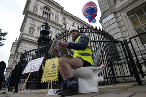 File - An activist sits on a toilet at the entrance to Downing Street to protest against raw sewage dumping in the rivers and seas around the UK after leaving the EU in London, Tuesday, Oct. 26, 2021.