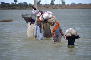 A displaced family wades through a flooded area after heavy rainfall, in Jaffarabad, a district of Pakistan's southwestern Baluchistan province, Wednesday, Aug. 24, 2022.