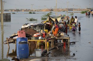 Families sit near their belongings surrounded by floodwaters, in Sohbat Pur city of Jaffarabad, a district of Pakistan's southwestern Baluchistan province, Sunday, Aug. 28, 2022