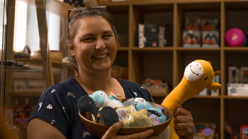 Woman holding sensory toys including a giraffe inside a store.