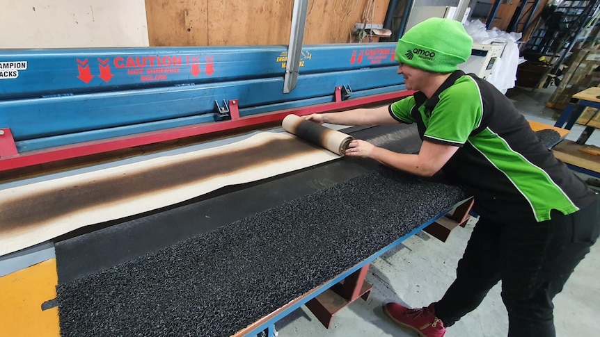 A man making a mat on a machine that looks like a press.