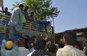 Displaced families who fled their flood-hit homes line up to receive food aid as they take refuge at an open area of Multan, Pakistan, Wednesday, Aug. 31, 2022.