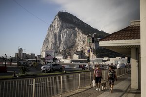 Backdropped by the Gibraltar rock, people cross the Gibraltar airport runway, Thursday, June, 24, 2021.