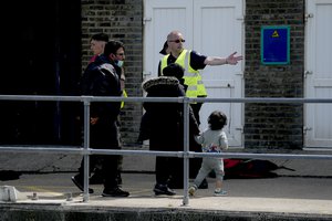 File - People thought to be migrants who undertook the crossing from France in small boats and were picked up in the Channel, are directed to board a waiting transfer bus after being disembarked from a British border force vessel, in Dover, south east England, Friday, June 17, 2022.