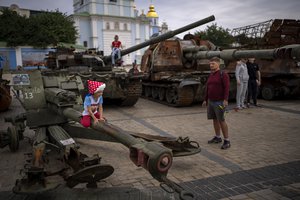 Children play jumping on destroyed Russian military vehicles displayed in central Kyiv, Ukraine, Saturday, Sept. 3, 2022.