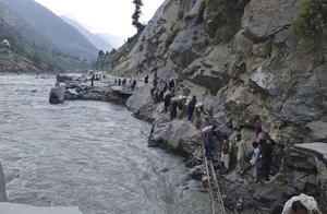 Local residents cross a portion of road destroyed by floodwaters in Kalam Valley in northern Pakistan, Sunday, Sept. 4, 2022.