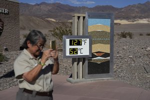 People visit a thermometer at the Furnace Creek Visitor Center, Thursday, Sept. 1, 2022, in Death Valley National Park, Calif. The thermometer is not official but is a popular photo spot.