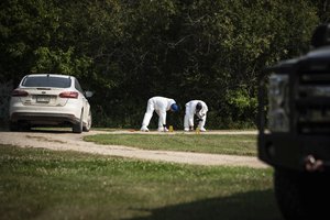 Investigators examine the crime scene outside the home of Wes Petterson in Weldon, Saskatchewan, Monday, Sept. 5, 2022. Petterson, 77, was killed in a series of stabbings in the area on Sunday.