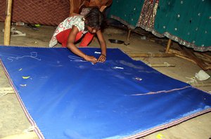 File - A young Indian girl weaves sleeping cloth mats in Jammu,India. A recent UN report suggests modern-day slavery is on the increase.