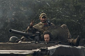 A Ukrainian soldier shows a V-sign atop a vehicle in Izium, Kharkiv region, Ukraine, Tuesday, Sept. 13, 2022