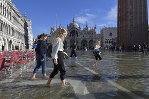 People walk in a flooded St. Mark's Square in Venice, Italy, Friday, Nov. 5, 2021