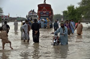 People navigate through a flooded road caused by heavy monsoon rains, in Nasirabad, a district of Pakistan's southwestern Baluchistan province, Aug. 22, 2022