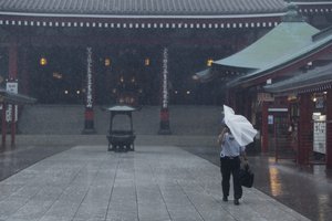 A man struggles with his umbrella as he was visiting to pray at the famed Sensoji temple in Tokyo, Friday, Oct. 1, 2021