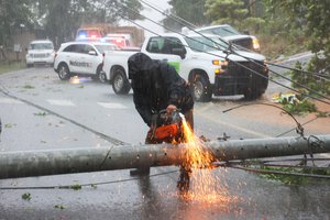 A worker cuts an electricity pole that was downed by Hurricane Fiona as it blocks a road in Cayey, Puerto Rico, Sunday, Sept. 18, 2022