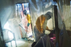 In this Saturday, July 13, 2019 file photo, health workers wearing protective suits tend to an Ebola victim kept in an isolation tent in Beni, Congo.