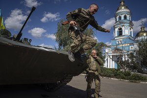 A Ukrainian serviceman jumps from an armored personnel carrier in the recently retaken area of Izium, Ukraine, Monday, Sept. 19, 2022