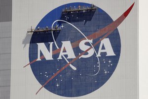 FILE - Workers on scaffolding repaint the NASA logo near the top of the Vehicle Assembly Building at the Kennedy Space Center in Cape Canaveral, Fla., Wednesday, May 20, 2020.