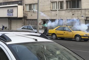 In this Tuesday, Sept. 20, 2022, photo taken by an individual not employed by the Associated Press and obtained by the AP outside Iran, a protester throws a tear gas back at the anti-riot police during a protest over the death of a young woman who had been detained for violating the country's conservative dress code, in downtown Tehran, Iran