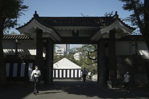 People go through a gate as they walk towards the building to be used for the state funeral of former Prime Minister Shinzo Abe as authorities have deployed extra officers to beef up securities in Tokyo, Monday, Sept. 26, 2022.