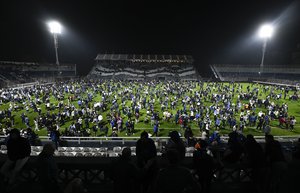 Fans of Gimnasia de La Plata take to the pitch after tear gas flooded the stadium during a local tournament soccer match between Gimnasia de La Plata and Boca Juniors in La Plata, Argentina, Thursday, Oct. 6, 2022