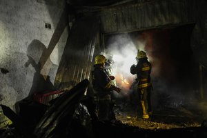 Ukrainian firefighters work among debris following a Russian shelling in Kharkiv, Ukraine, early Saturday, Oct. 8, 2022