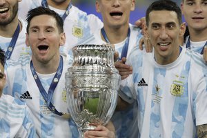 Argentina's Lionel Messi, left, and teammate Angel Di Maria celebrate with teammates after beating 1-0 Brazil in the Copa America final soccer match at the Maracana stadium in Rio de Janeiro, Brazil, Saturday, July 10, 2021