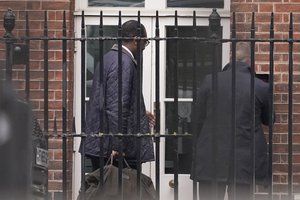 Britain's Treasury chief Kwasi Kwarteng, left, arrives back from the US at the rear of Downing Street in London, Friday, Oct. 14, 2022