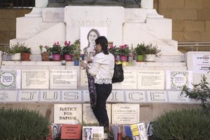 Mandy Mallia, sister of late journalist Daphne Caruana Galizia, lights candles in front of a picture of her sister in Valletta, Malta, Friday, Oct. 14, 2022