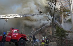 Firefighters work after a drone fired on buildings in Kyiv, Ukraine, Monday, Oct. 17, 2022