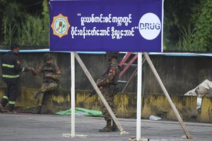 Two military soldiers and a firefighter provide security during a destruction ceremony on the outskirts of Yangon, Myanmar, Saturday, June 26, 2021