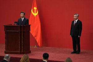 Chinese President Xi Jinping speaks as Li Xi listens at an event to introduce new members of the Politburo Standing Committee at the Great Hall of the People in Beijing, Sunday, Oct. 23, 2022