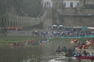 Rescuers sit on boats as Indian Prime Minister Narendra Modi, above, looks at a cable pedestrian bridge that collapsed Sunday in Morbi town of western state Gujarat, India, Tuesday, Nov. 1, 2022.