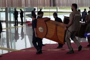 Workers carry the podium used by Brazilian President Jair Bolsonaro before he expected to speak from his official residence of Alvorada Palace in Brasilia, Brazil, Tuesday, Nov. 1, 2022. Bolsonaro lost reelection in the Oct. 30 presidential runoff but hasn’t spoken publicly since official electoral results were released Sunday night, nor has he phoned former President Luiz Inacio Lula da Silva to concede.