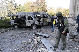 Investigators inspect a site after shelling near an administrative building, in Donetsk, the capital of Donetsk People's Republic, eastern in Ukraine, Sunday, Oct. 16, 2022