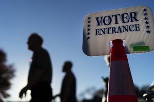 Voters pass a sign outside a polling site in Warwick, R.I., Monday, Nov. 7, 2022, after casting their ballots on the last day of early voting before the midterm election.