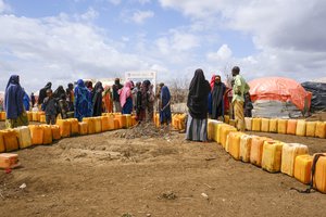 Somalis displaced by drought wait in line to fill jerrycans with water distributed by the Norwegian Refugee Council, on the outskirts of Baidoa, in Somalia Saturday, Oct. 29, 2022.