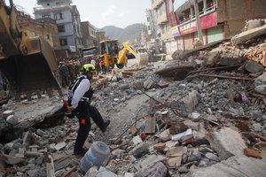 A rescue worker from USAID inspects the site of a building that collapsed in an earthquake in Kathmandu, Nepal, Tuesday, May 12, 2015.