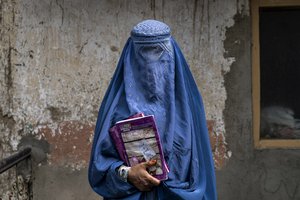 File - Arefeh 40-year-old, an Afghan woman leaves an underground school in full burka, in Kabul, Afghanistan, Saturday, July 30, 2022. She attends this underground school with her daughter who is not allowed to go to public school. For most teenage girls in Afghanistan, it’s been a year since they set foot in a classroom.