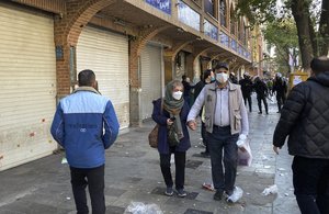 People walk in front of closed shops of Tehran's Grand Bazaar as anti-riot police controls the protest scene, Iran, Tuesday, Nov. 15, 2022.