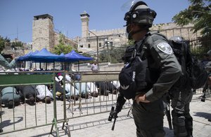 Israeli police officers stand guard during Palestinians Friday prayers at a protest against construction access in being built on the Jewish side at the Ibrahimi Mosque, which Jews call the Tomb of the Patriarchs, in the West Bank city of Hebron, Friday, Aug. 13, 2021.